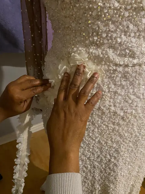 Hand-applying a floral sash to a pearl and sequin gown in our Birmingham studio